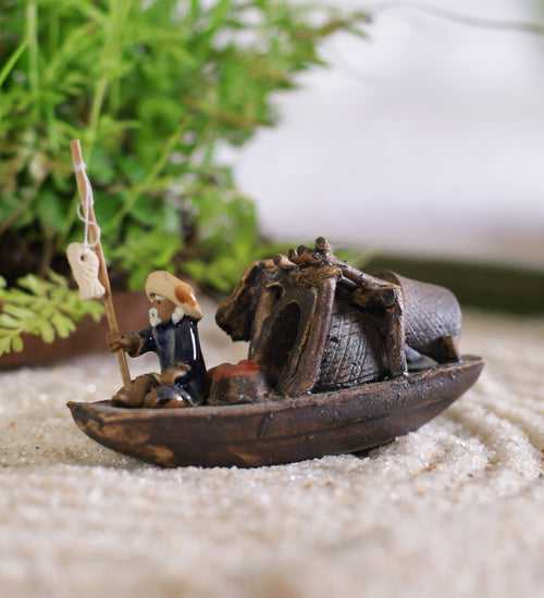 Old fisherman in blue sitting on boat with fishing rod