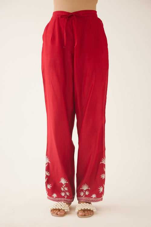 Red silk chanderi straight pants with off white silk thread embroidery at hem.