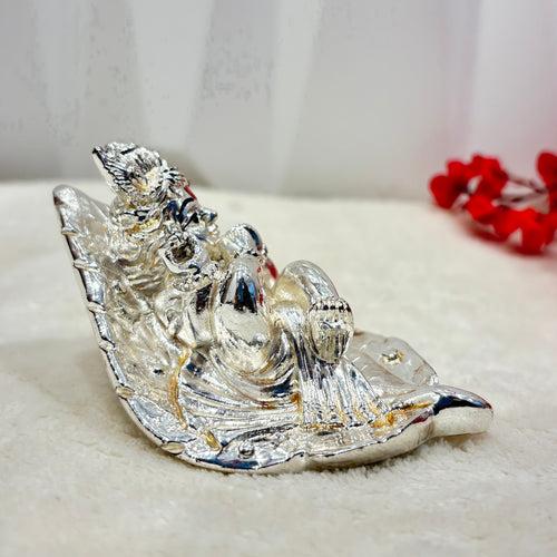 Bring a touch of whimsy to your home with our Silver Baby Krishna figurine, nestled in a delicate leaf. Standing at 5.7 inches, this playful piece adds a playful and charming touch to any room. Perfect for lovers of unique and quirky Decor.